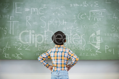 Schoolboy looking mathematics on chalkboard in classroom