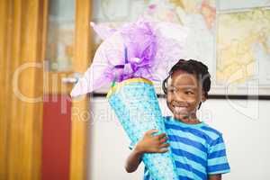 Smiling schoolboy holding gift in classroom