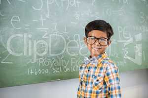 Portrait of schoolboy smiling against chalkboard in classroom