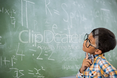 Thoughtful schoolboy looking at mathematical problem in classroom