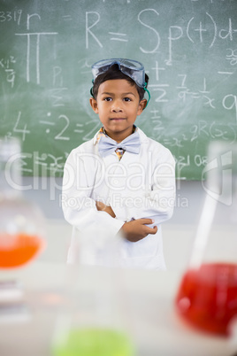 Schoolboy standing in classroom with chemical flask in foreground