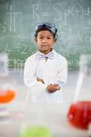 Schoolboy standing in classroom with chemical flask in foreground