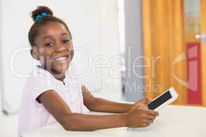 Smiling schoolgirl using digital tablet in classroom at school