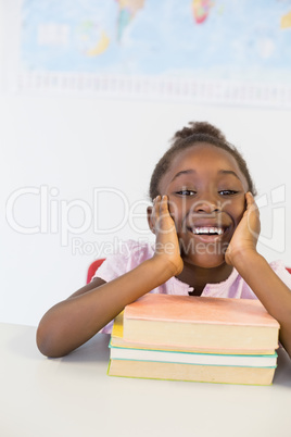 Portrait of smiling girl with books in classroom