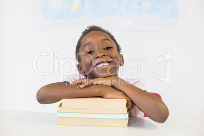 Portrait of smiling girl with books in classroom