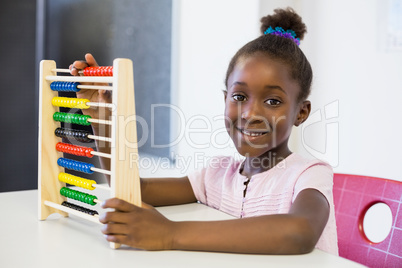 Schoolgirl using a maths abacus in classroom