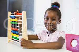 Schoolgirl using a maths abacus in classroom