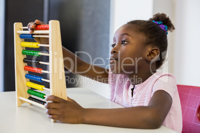 Schoolgirl using a maths abacus in classroom