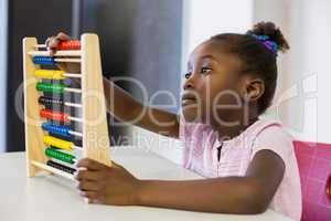 Schoolgirl using a maths abacus in classroom