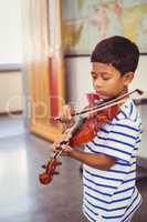 Schoolboy playing violin in classroom