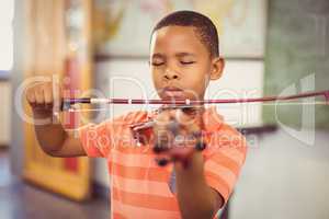 Schoolboy playing violin in classroom