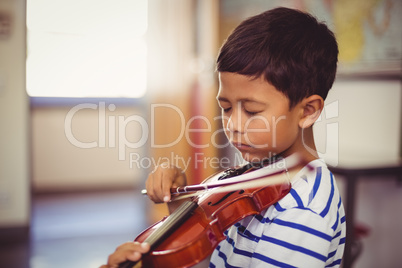 Schoolboy playing violin in classroom