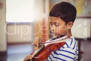 Schoolboy playing violin in classroom