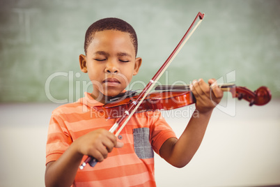 Schoolboy playing violin in classroom