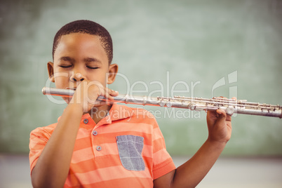 Schoolboy playing flute in classroom