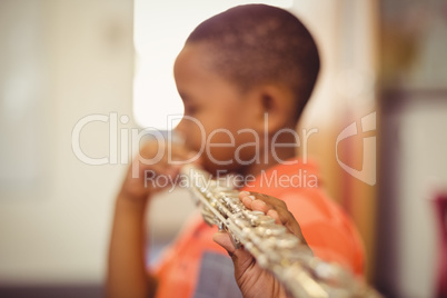 Schoolboy playing flute in classroom