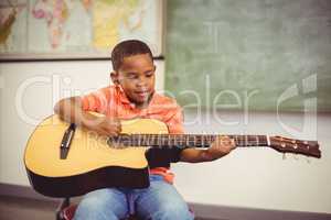 Schoolboy playing guitar in classroom