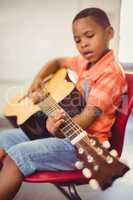 Schoolboy playing guitar in classroom