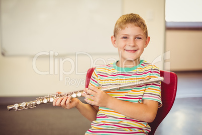 Portrait of smiling schoolboy playing flute in classroom Portrait of smiling schoolboy playing flute in classroom
