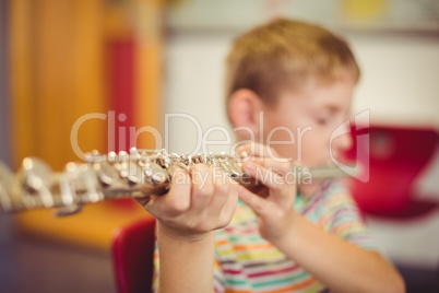 Schoolboy playing flute in classroom