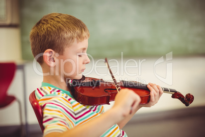 Schoolboy playing violin in classroom