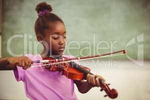 Schoolgirl playing violin in classroom