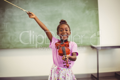 Portrait of smiling schoolgirl playing violin in classroom