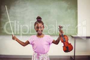 Portrait of smiling schoolgirl holding violin in classroom