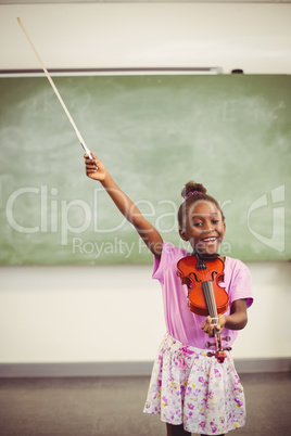 Portrait of smiling schoolgirl playing violin in classroom