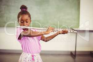 Schoolgirl playing flute in classroom