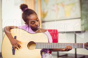 Schoolgirl playing guitar in classroom
