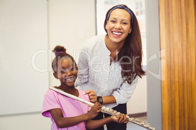 Portrait of teacher and girl with flute in classroom