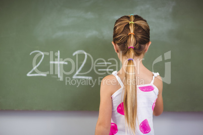 Schoolgirl doing mathematics on chalkboard in classroom