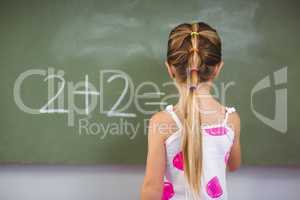 Schoolgirl doing mathematics on chalkboard in classroom