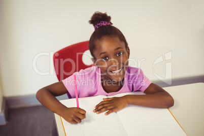 Portrait of schoolgirl doing homework in classroom