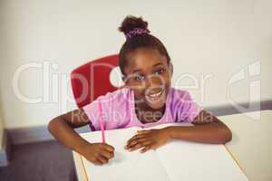 Portrait of schoolgirl doing homework in classroom