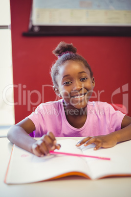 Portrait of schoolgirl doing homework in classroom