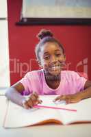 Portrait of schoolgirl doing homework in classroom