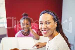 Portrait of teacher helping a girl with her homework in classroom