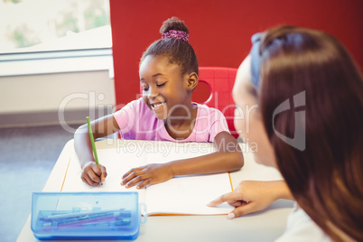 Teacher helping a girl with her homework in classroom