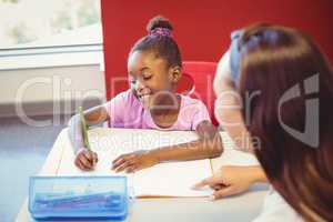 Teacher helping a girl with her homework in classroom