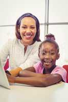 Teacher and school girl using digital tablet in classroom