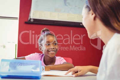 Teacher helping a girl with her homework in classroom