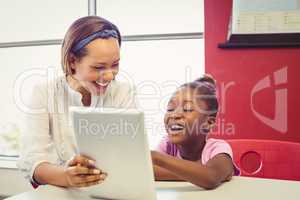 Teacher and school girl using digital tablet in classroom