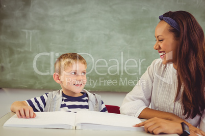 Teacher helping a boy with his homework in classroom