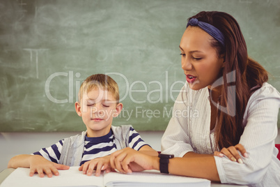 Teacher helping a boy with his homework in classroom