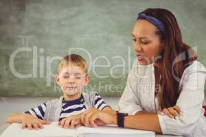 Teacher helping a boy with his homework in classroom