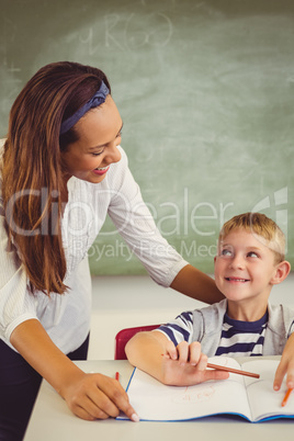 Teacher helping a boy with his homework in classroom