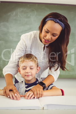 Teacher helping a boy with his homework in classroom