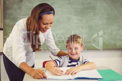 Teacher helping a boy with his homework in classroom